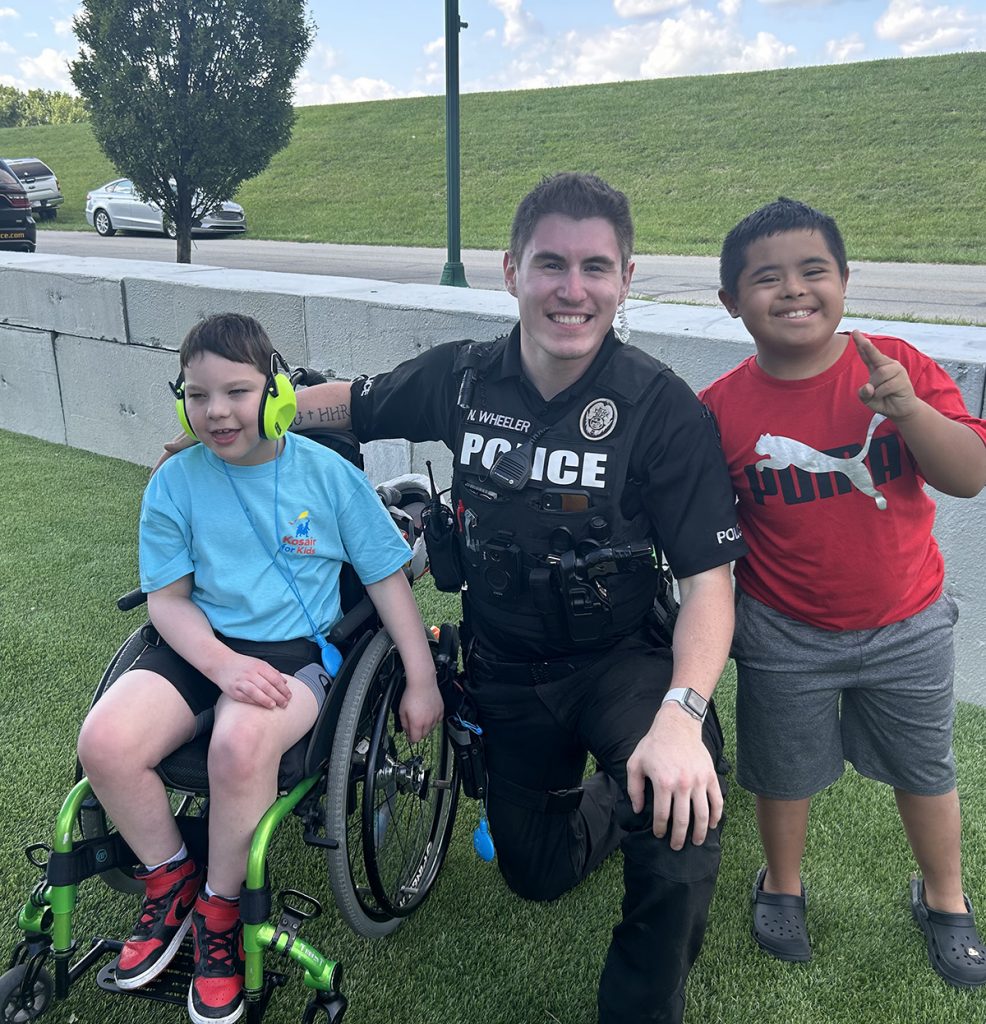 Kids pose with police officer.